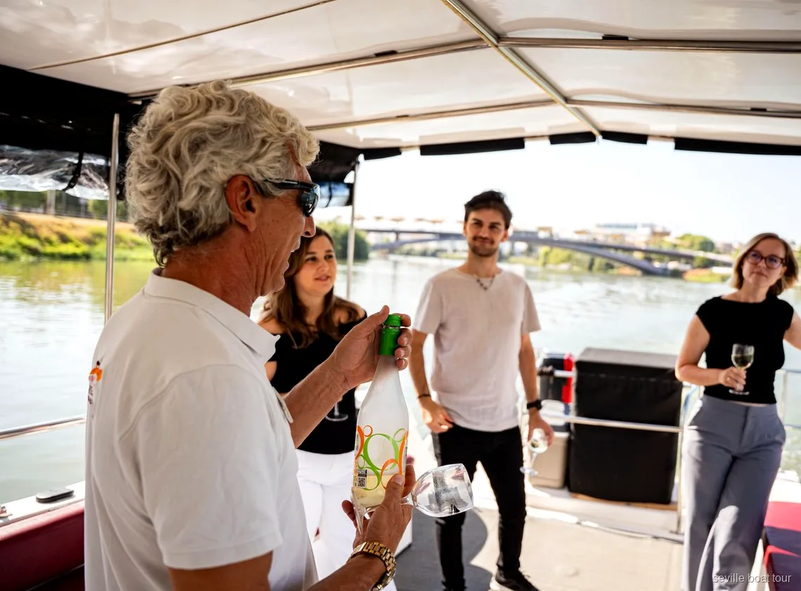 Accompagnatore che serve vino agli ospiti sotto il tendalino di un giro in barca a Siviglia